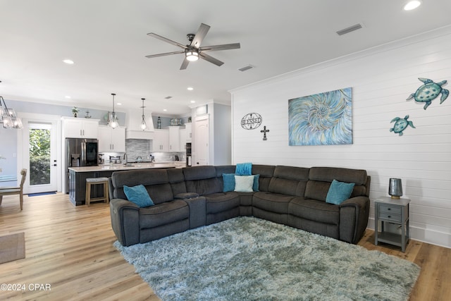 living room with ceiling fan, light hardwood / wood-style floors, and crown molding