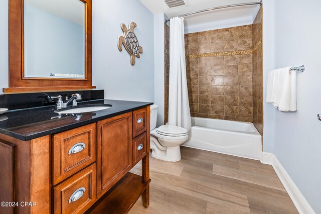 full bathroom featuring hardwood / wood-style floors, vanity, toilet, and shower / tub combo with curtain