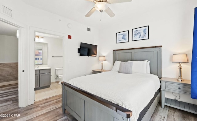 bedroom featuring light wood-type flooring, connected bathroom, and ceiling fan