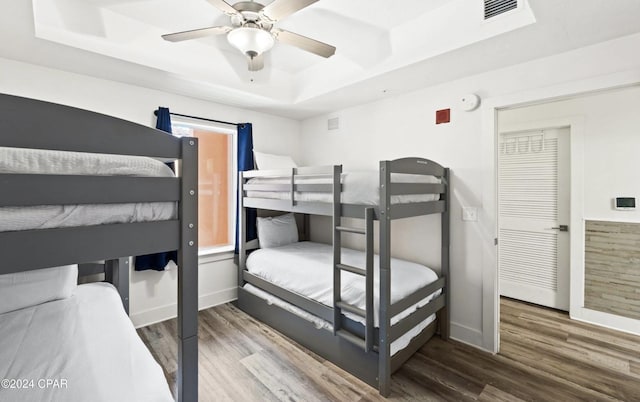 bedroom featuring hardwood / wood-style flooring, ceiling fan, and a raised ceiling