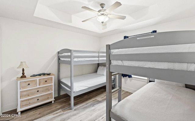 bedroom featuring hardwood / wood-style floors, ceiling fan, and a raised ceiling