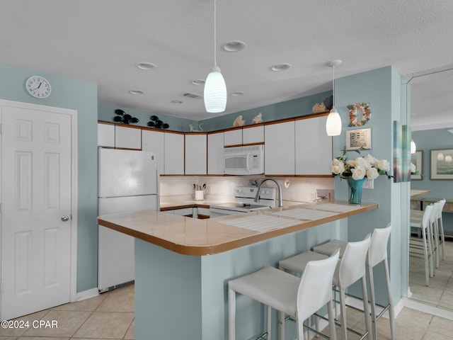 kitchen with backsplash, white cabinetry, decorative light fixtures, and white appliances