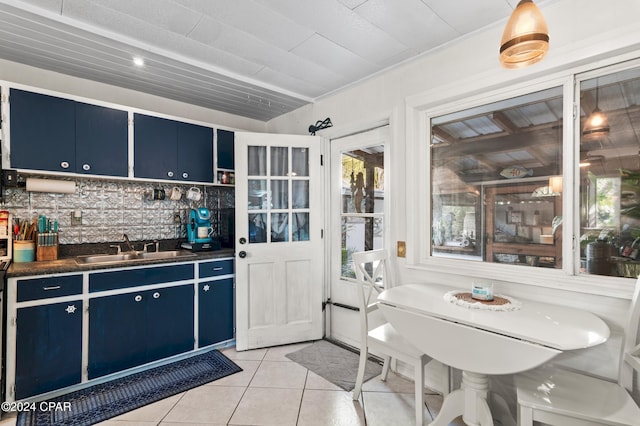 kitchen featuring sink, backsplash, blue cabinets, and light tile patterned flooring