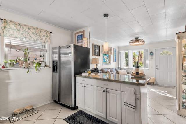 kitchen featuring kitchen peninsula, stainless steel fridge with ice dispenser, decorative light fixtures, light tile patterned flooring, and white cabinetry