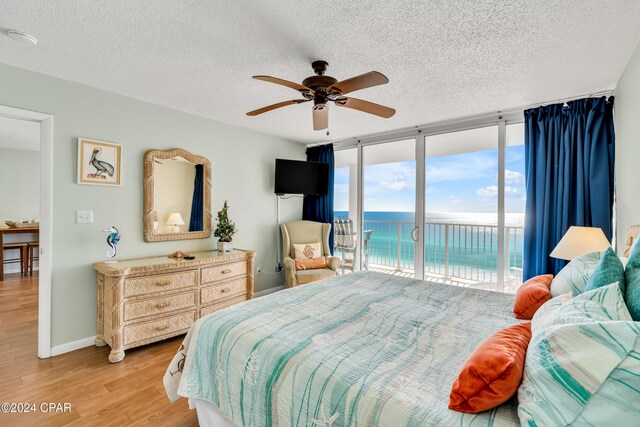 bedroom with expansive windows, a textured ceiling, access to exterior, and light wood-type flooring