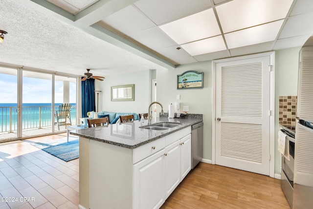 kitchen with white cabinets, appliances with stainless steel finishes, sink, kitchen peninsula, and a water view