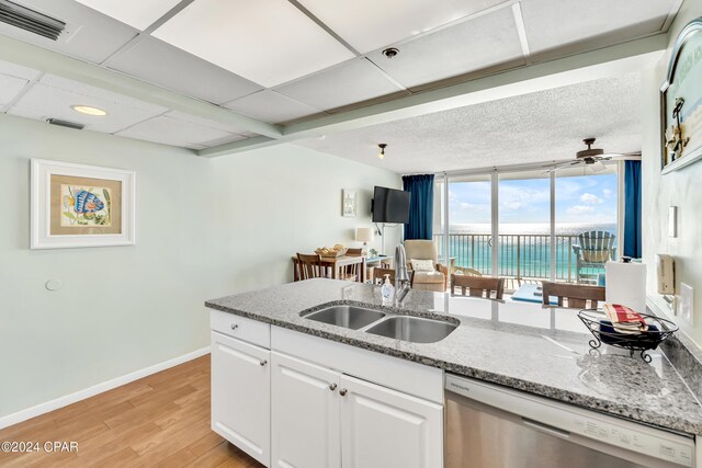 kitchen featuring white cabinetry, light hardwood / wood-style floors, dishwasher, expansive windows, and sink