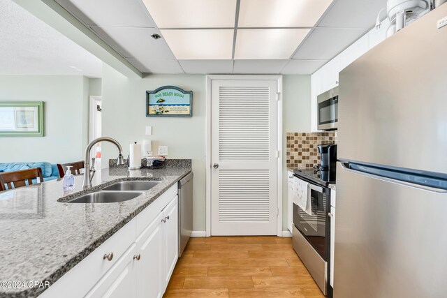 kitchen featuring decorative backsplash, sink, white cabinetry, and appliances with stainless steel finishes