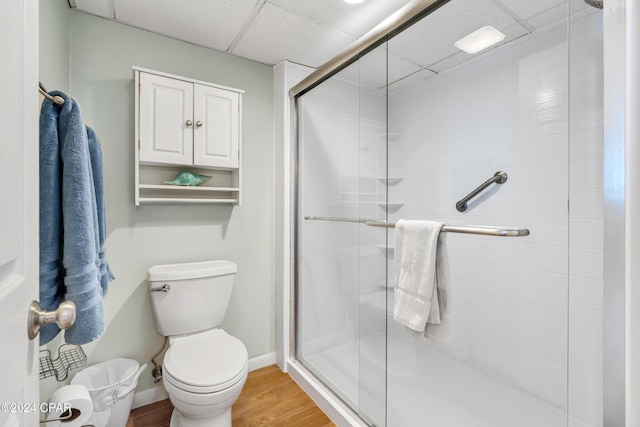 bathroom featuring toilet, hardwood / wood-style floors, a drop ceiling, and a shower with shower door