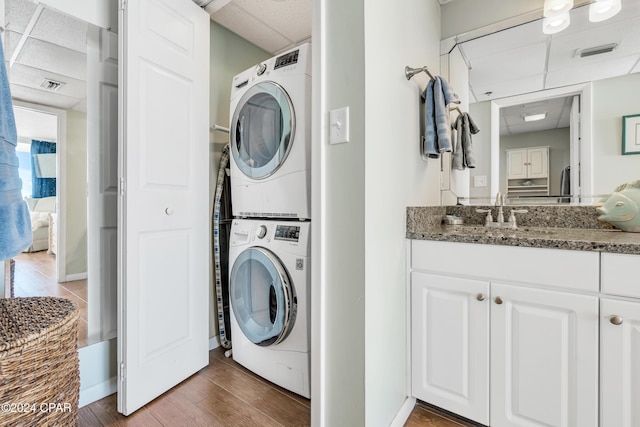 laundry room featuring sink, stacked washer / drying machine, and dark hardwood / wood-style floors