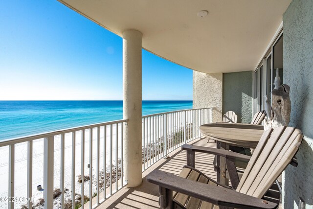 balcony with a water view and a view of the beach