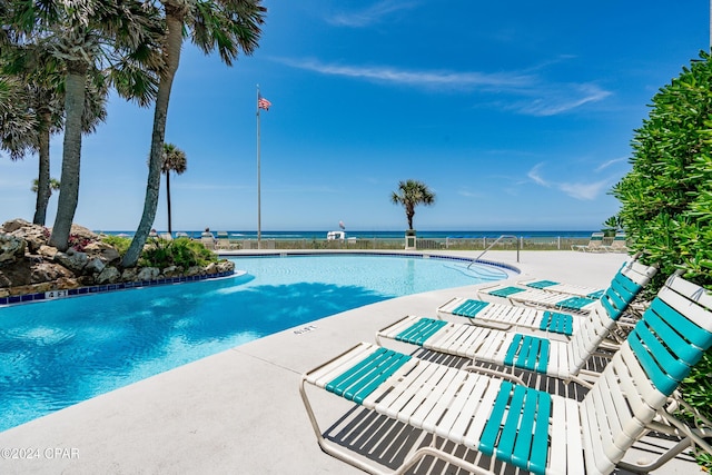 view of swimming pool featuring a patio and a water view