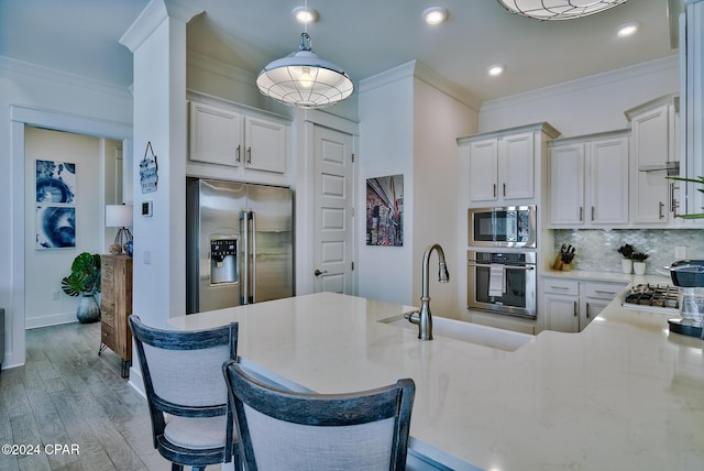 kitchen with light hardwood / wood-style floors, a breakfast bar, kitchen peninsula, and stainless steel appliances