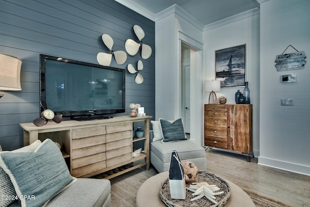 sitting room with wood walls, ornamental molding, and light hardwood / wood-style flooring