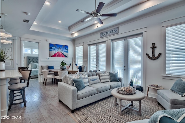 living room featuring ceiling fan, a tray ceiling, and hardwood / wood-style floors