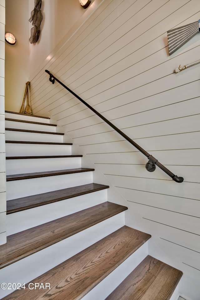 stairway featuring wooden walls