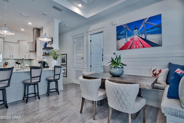 dining space featuring breakfast area, crown molding, hardwood / wood-style floors, and sink