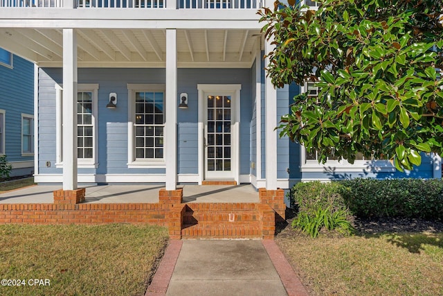 doorway to property featuring a yard and covered porch