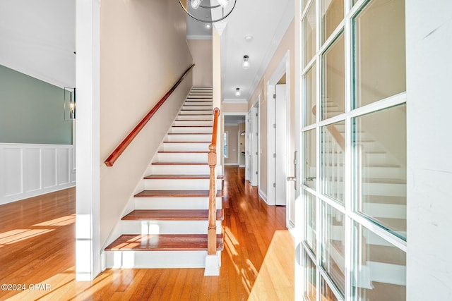 stairs featuring ornamental molding and hardwood / wood-style floors