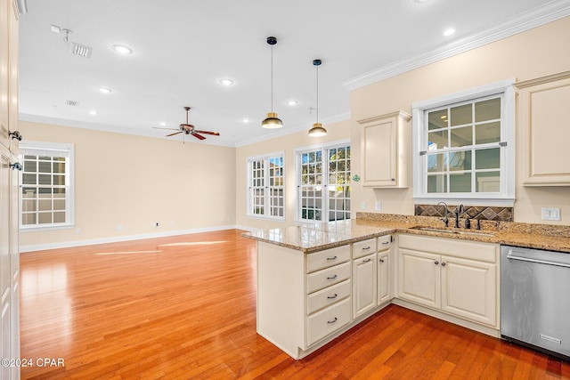 kitchen with pendant lighting, dishwasher, sink, ornamental molding, and light stone countertops