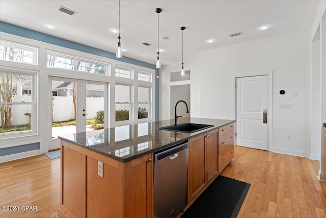 kitchen featuring a kitchen island with sink, french doors, sink, stainless steel dishwasher, and decorative light fixtures