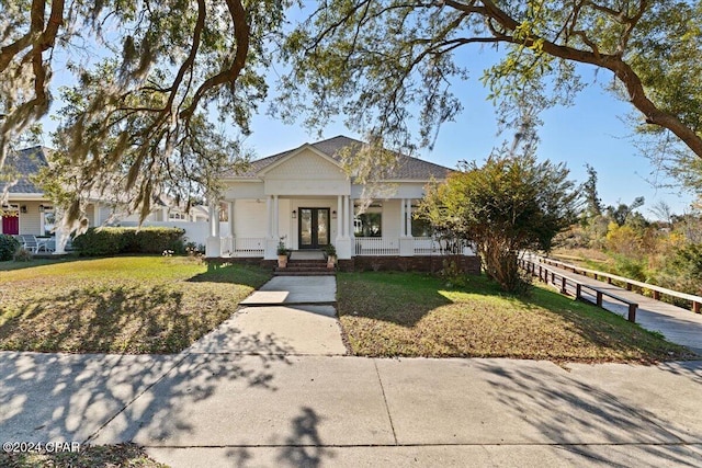 view of front of property with french doors, covered porch, and a front yard