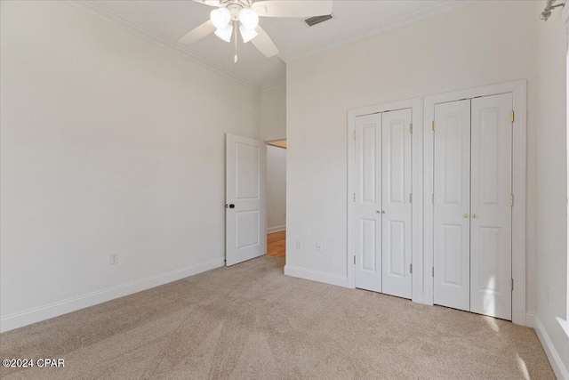 unfurnished bedroom featuring ceiling fan, light carpet, two closets, and ornamental molding