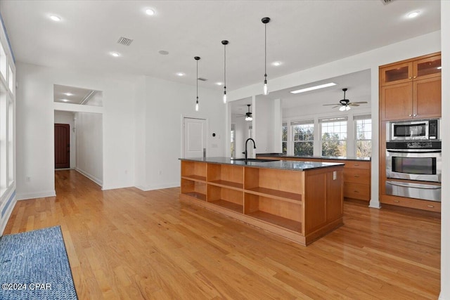 kitchen featuring pendant lighting, sink, ceiling fan, an island with sink, and appliances with stainless steel finishes