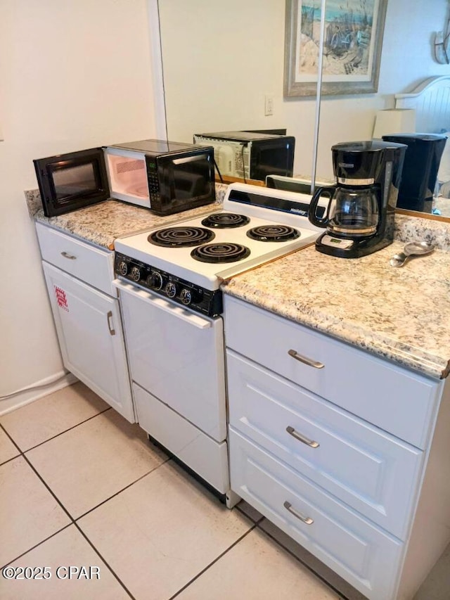 kitchen with light tile patterned floors, white range oven, and white cabinetry