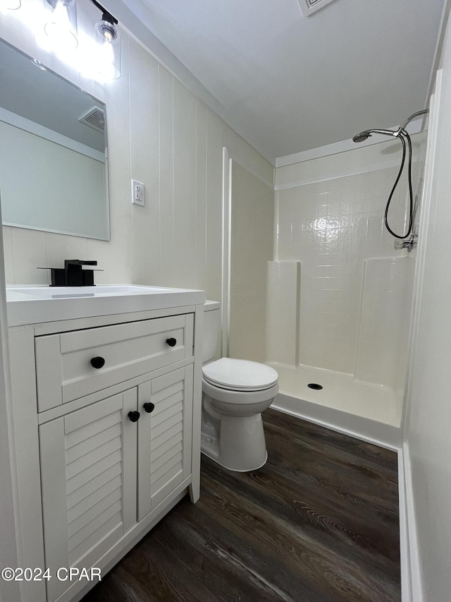 bathroom with toilet, hardwood / wood-style flooring, walk in shower, and vanity