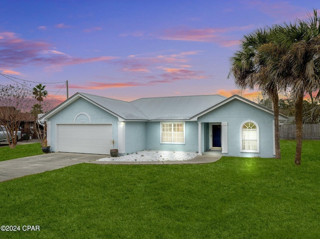 ranch-style house with a garage and a yard