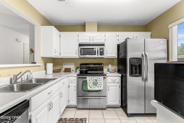 kitchen with sink, white cabinetry, a textured ceiling, stainless steel appliances, and light tile patterned floors