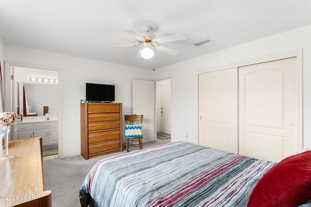 bedroom featuring ceiling fan, light colored carpet, ensuite bathroom, and a closet