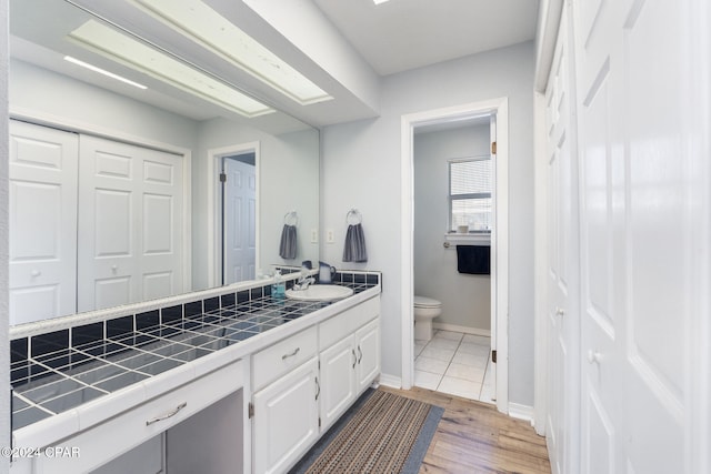 bathroom with hardwood / wood-style flooring, vanity, and toilet