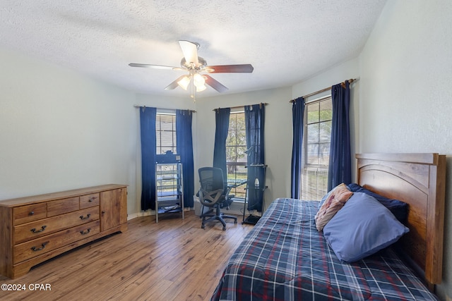 bedroom featuring ceiling fan, dark hardwood / wood-style floors, and a textured ceiling