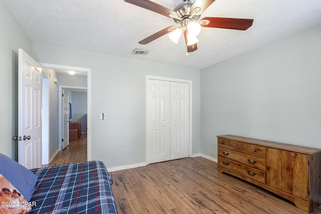 bedroom with hardwood / wood-style flooring, ceiling fan, a textured ceiling, and a closet