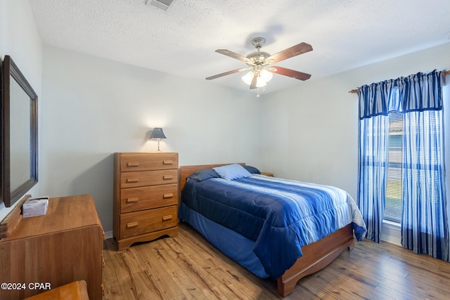 bedroom featuring ceiling fan, a textured ceiling, and light wood-type flooring