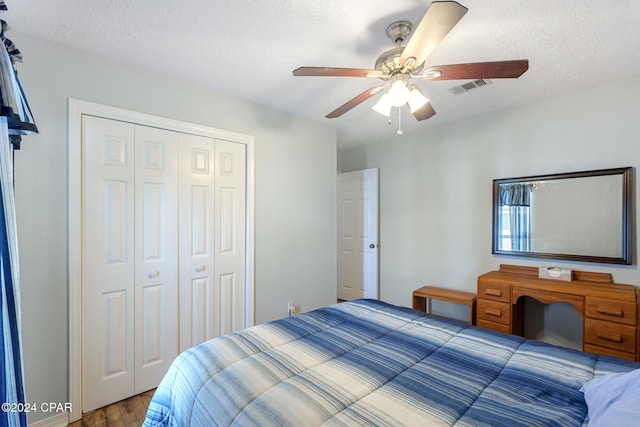 bedroom with a textured ceiling, a closet, dark wood-type flooring, and ceiling fan