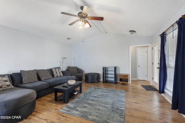 living room featuring vaulted ceiling with beams, ceiling fan, wood-type flooring, and a textured ceiling