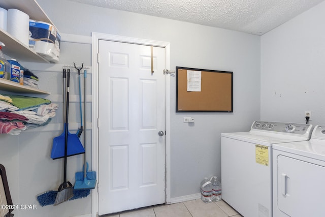 washroom featuring light tile patterned floors, washer and dryer, and a textured ceiling