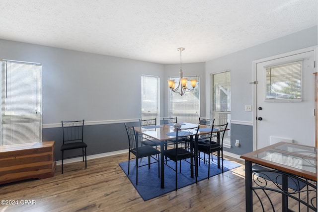 dining room featuring dark wood-type flooring, a textured ceiling, and an inviting chandelier