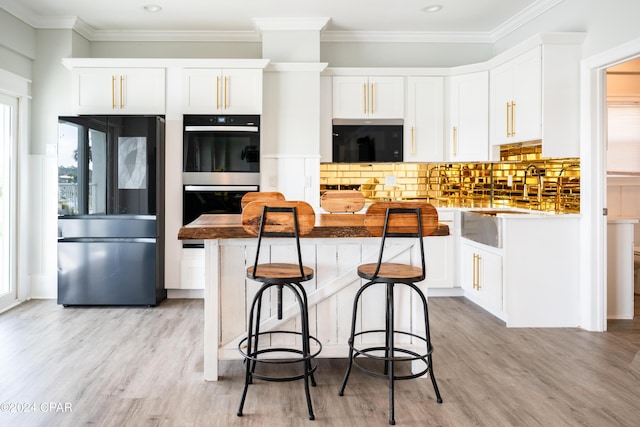 kitchen featuring black refrigerator, double oven, and white cabinetry