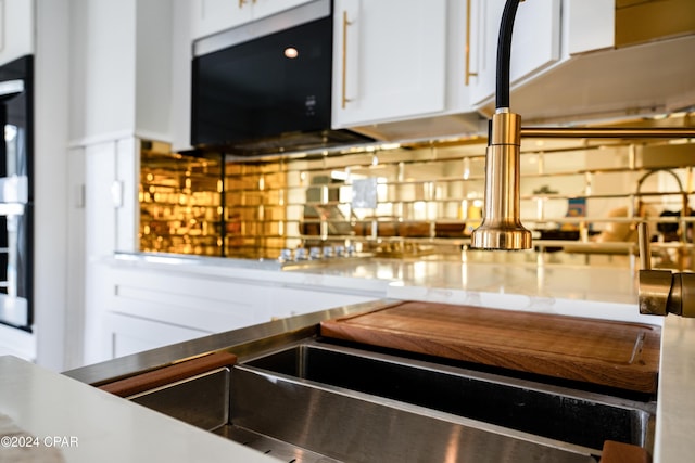 details featuring tasteful backsplash and white cabinets