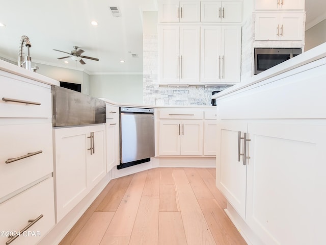 kitchen with white cabinetry, stainless steel appliances, decorative backsplash, ornamental molding, and ceiling fan