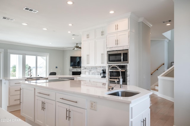 kitchen featuring white cabinetry, stainless steel appliances, sink, ceiling fan, and a center island with sink