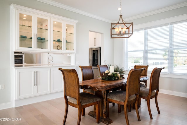 dining space with a notable chandelier, ornamental molding, light hardwood / wood-style flooring, and sink