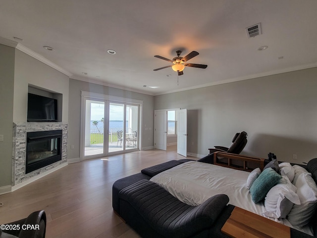 bedroom featuring ceiling fan, a fireplace, light hardwood / wood-style floors, access to outside, and crown molding