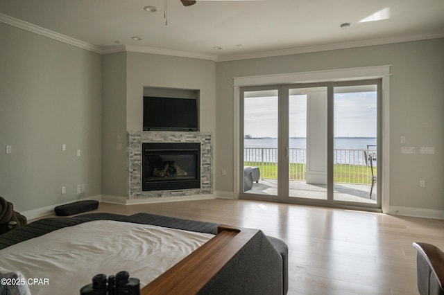 living room with ceiling fan, a stone fireplace, ornamental molding, and light hardwood / wood-style floors