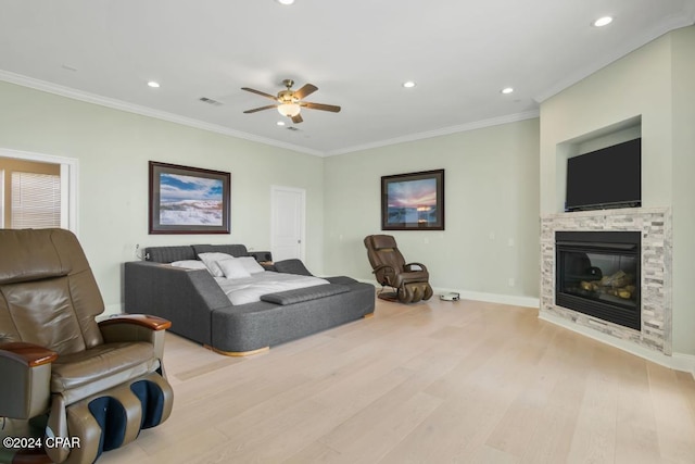 bedroom with ceiling fan, light wood-type flooring, a fireplace, and ornamental molding