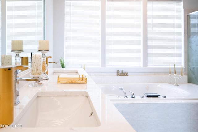 bathroom with a relaxing tiled tub and sink